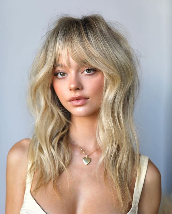 Chic Blonde Wavy Haircut with Layers and Bangs